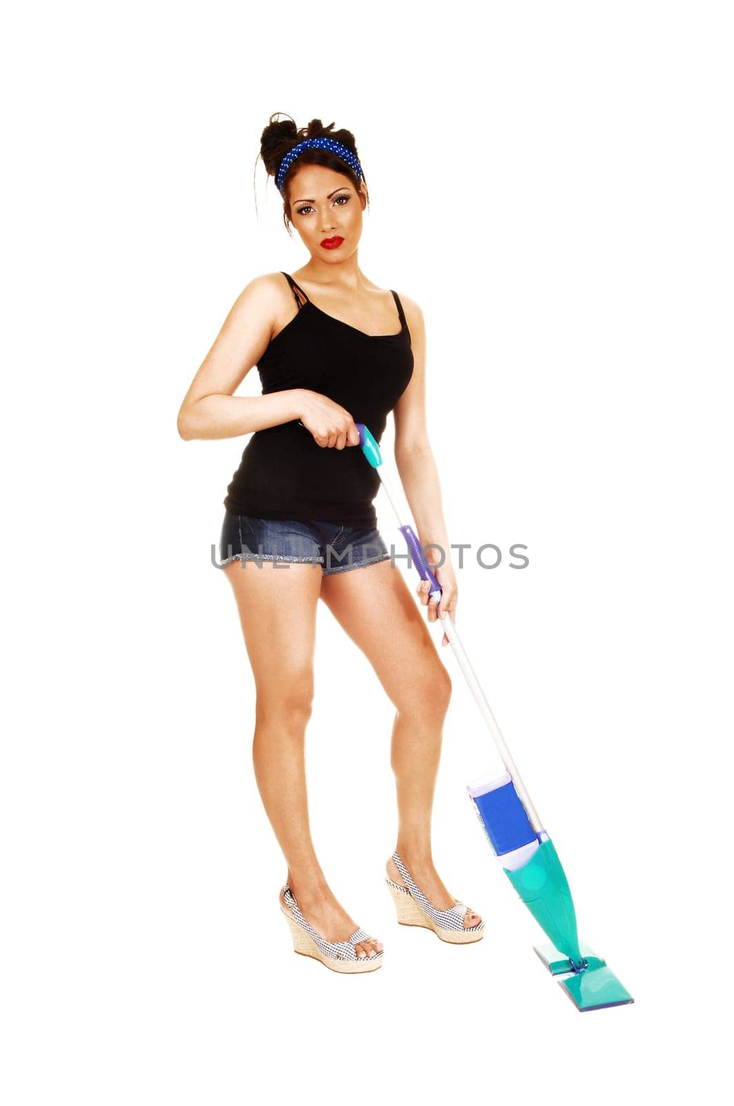 A lovely young woman standing with a cleaner for white background in shorts and a black top, cleaning the floor.