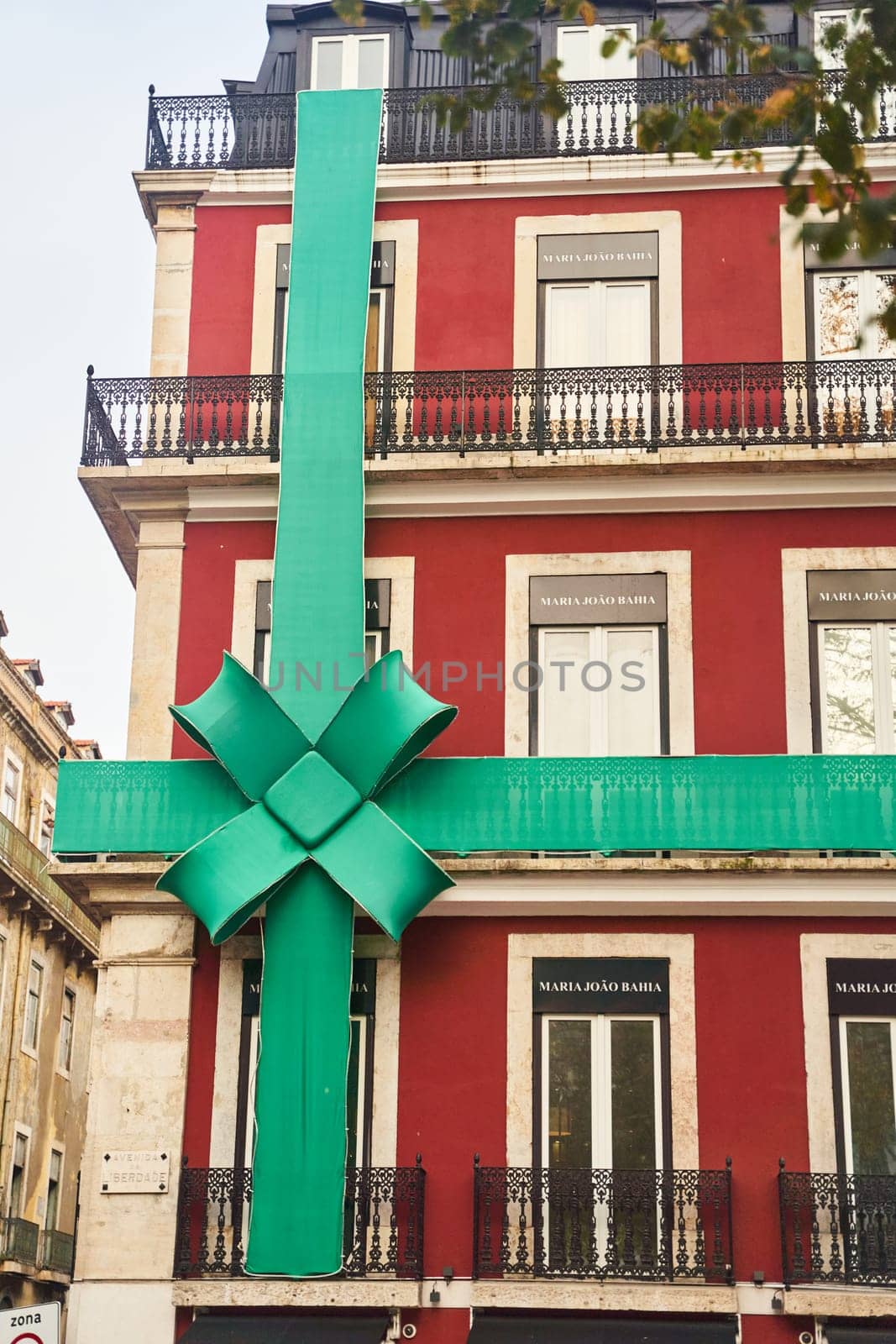 Lisbon, Portugal - 29.12.2022: A vibrant green ribbon decorates a charming red building, significantly enhancing its festive appeal