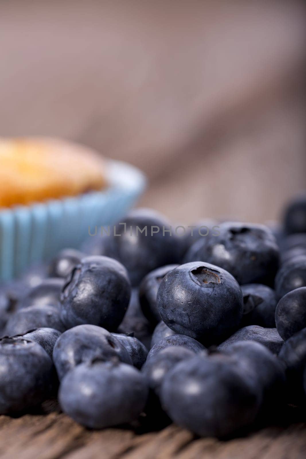 Blueberry muffin blurred lies in front of many fresh blueberries