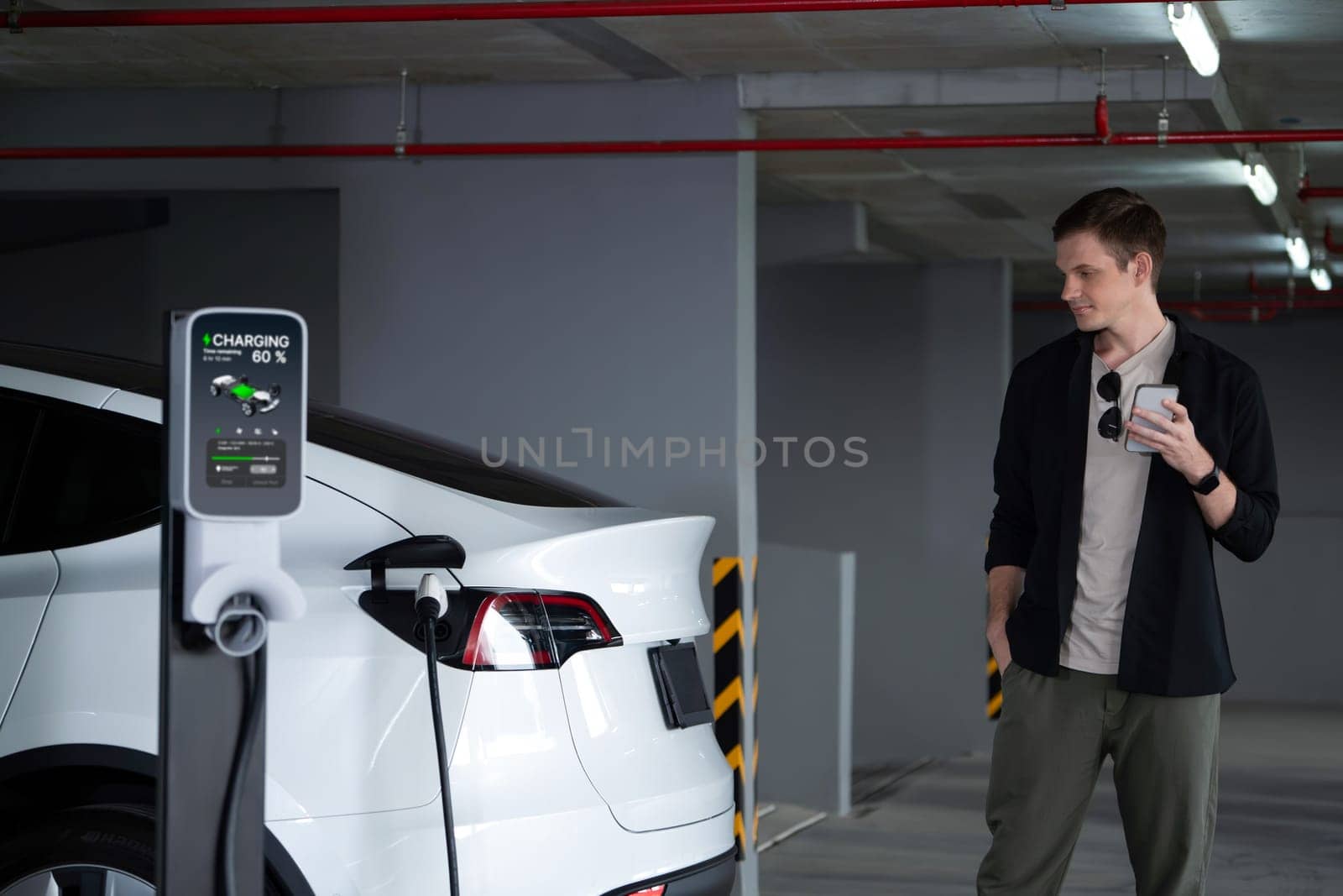 Young man travel with EV electric car to shopping center parking lot charging in downtown city showing urban sustainability lifestyle by green clean rechargeable energy of electric vehicle innards