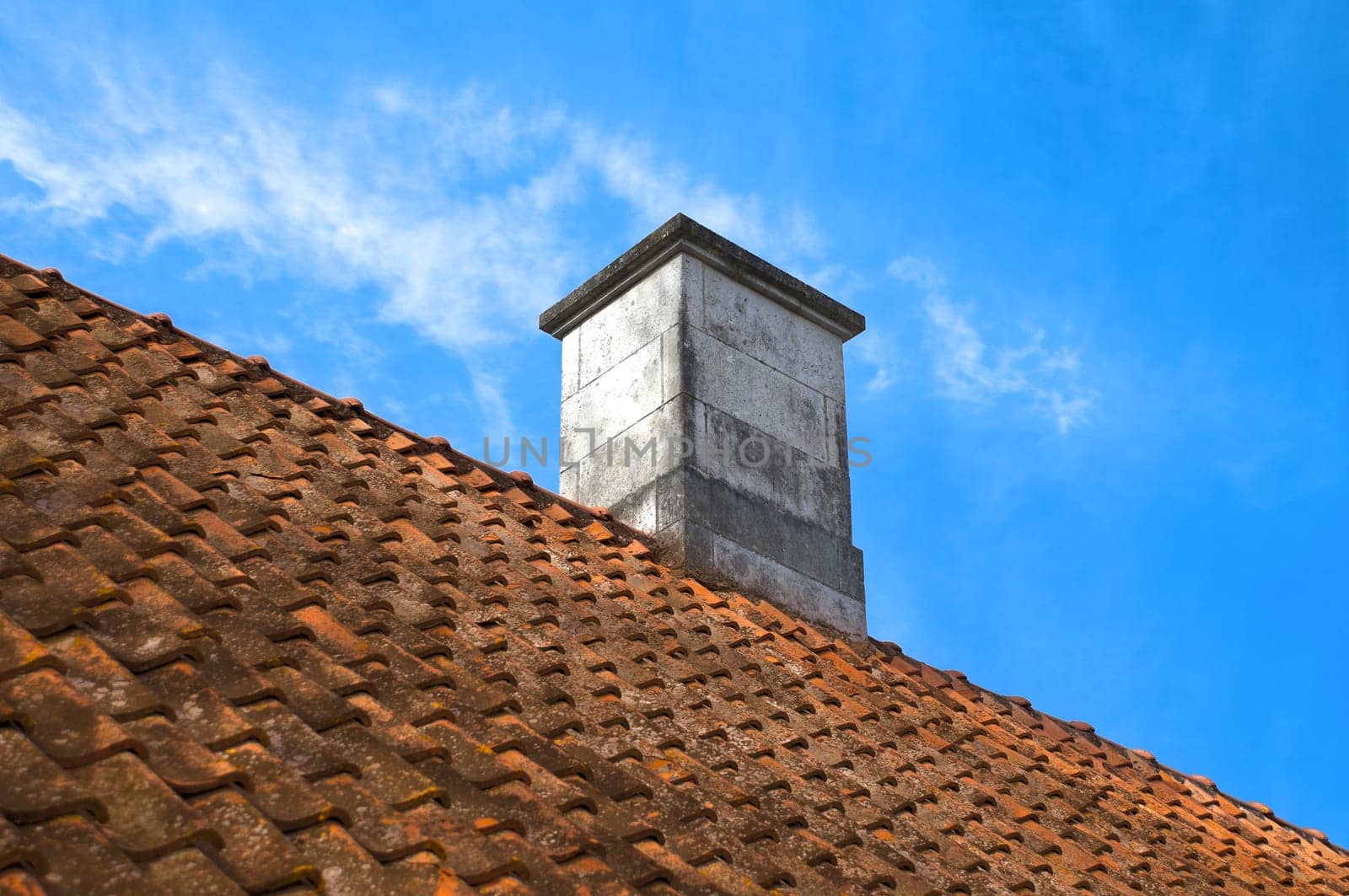 tiled roof top with  chimney with blue cloudy sky in background