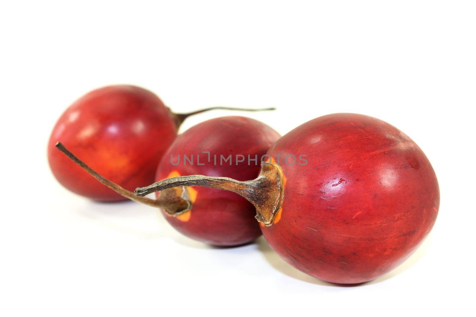 three red tamarillos against white background