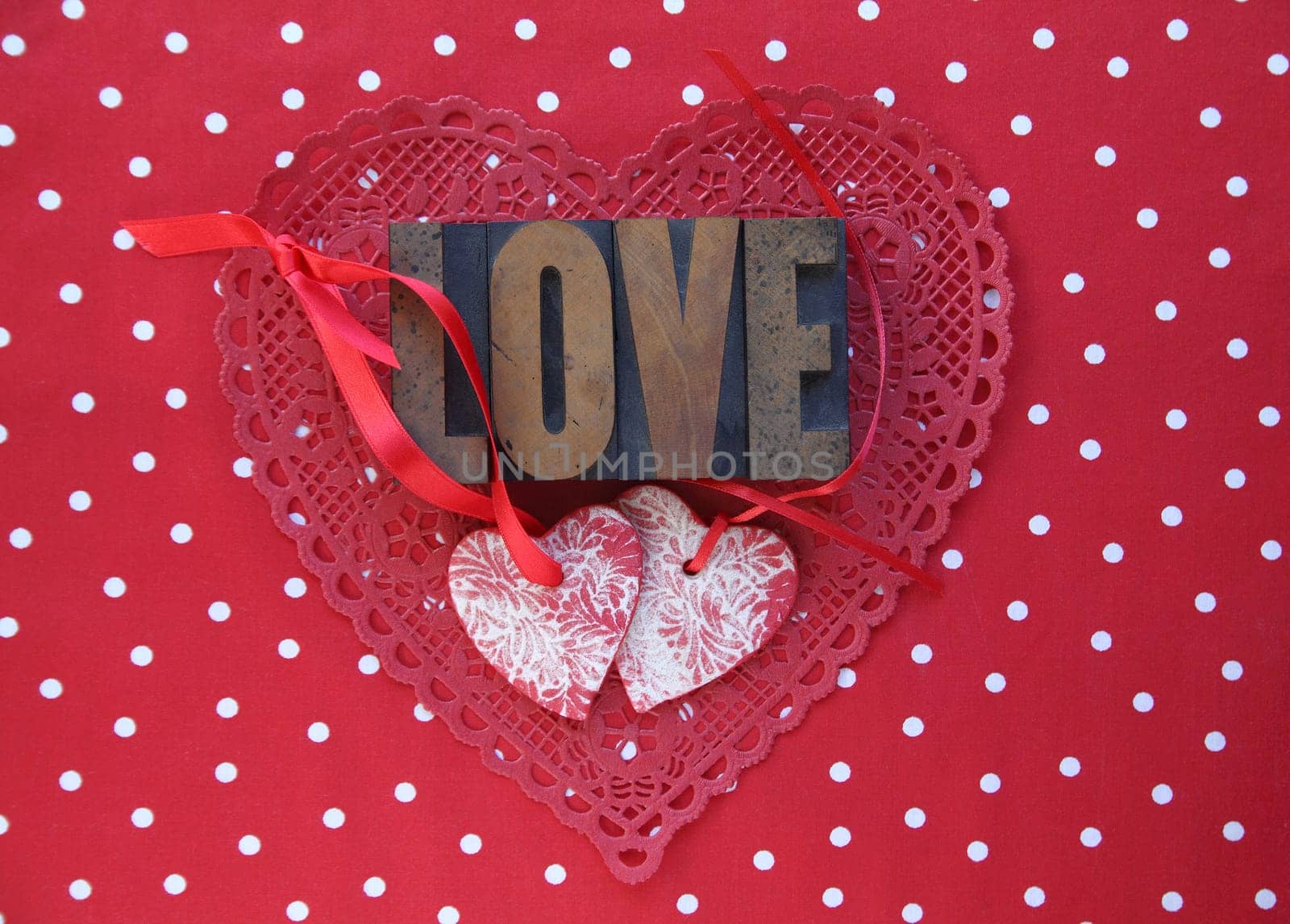 the word 'love' with heart ornaments and red ribbons on a red and white polka dot background