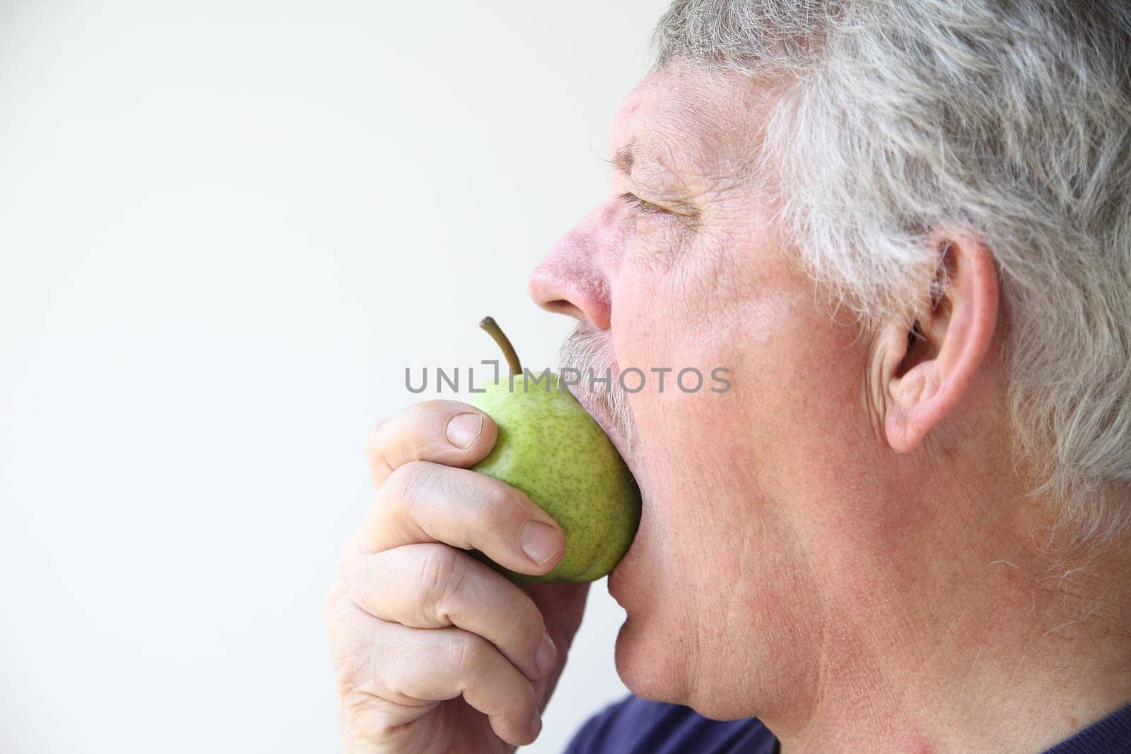 senior man eats a fresh pear