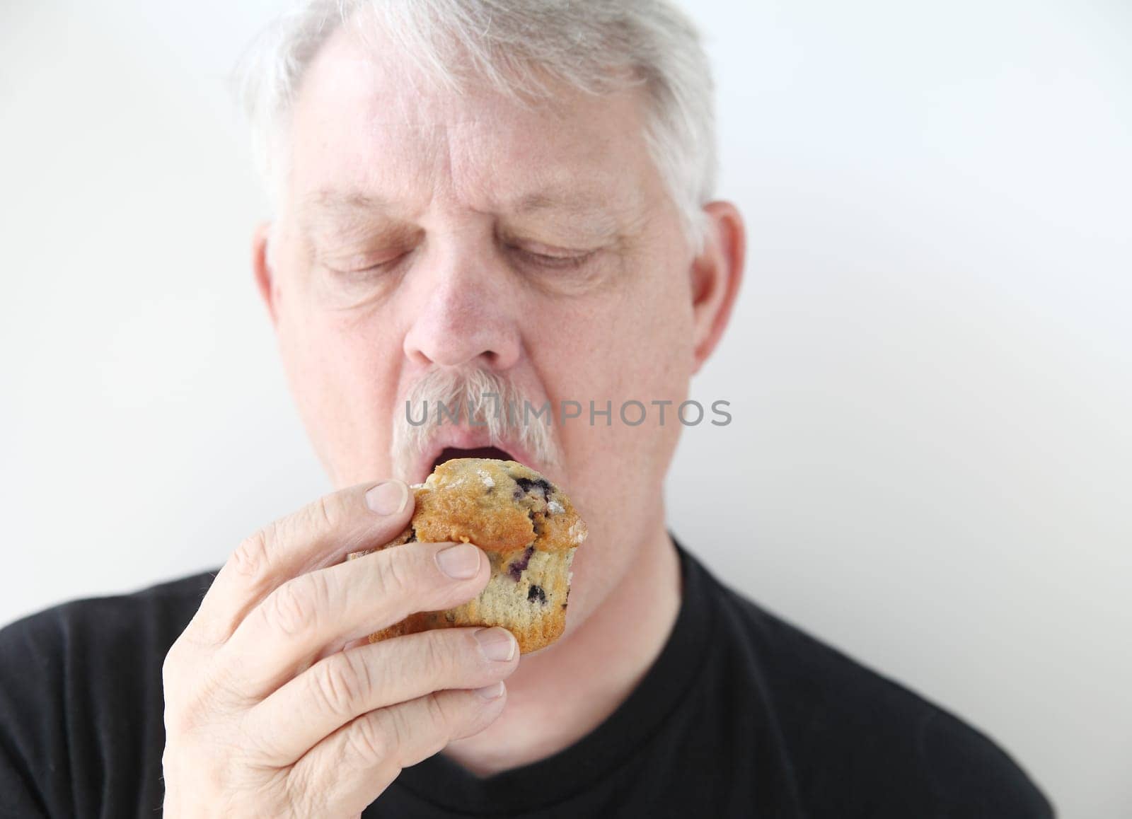 man eats a fruit muffin