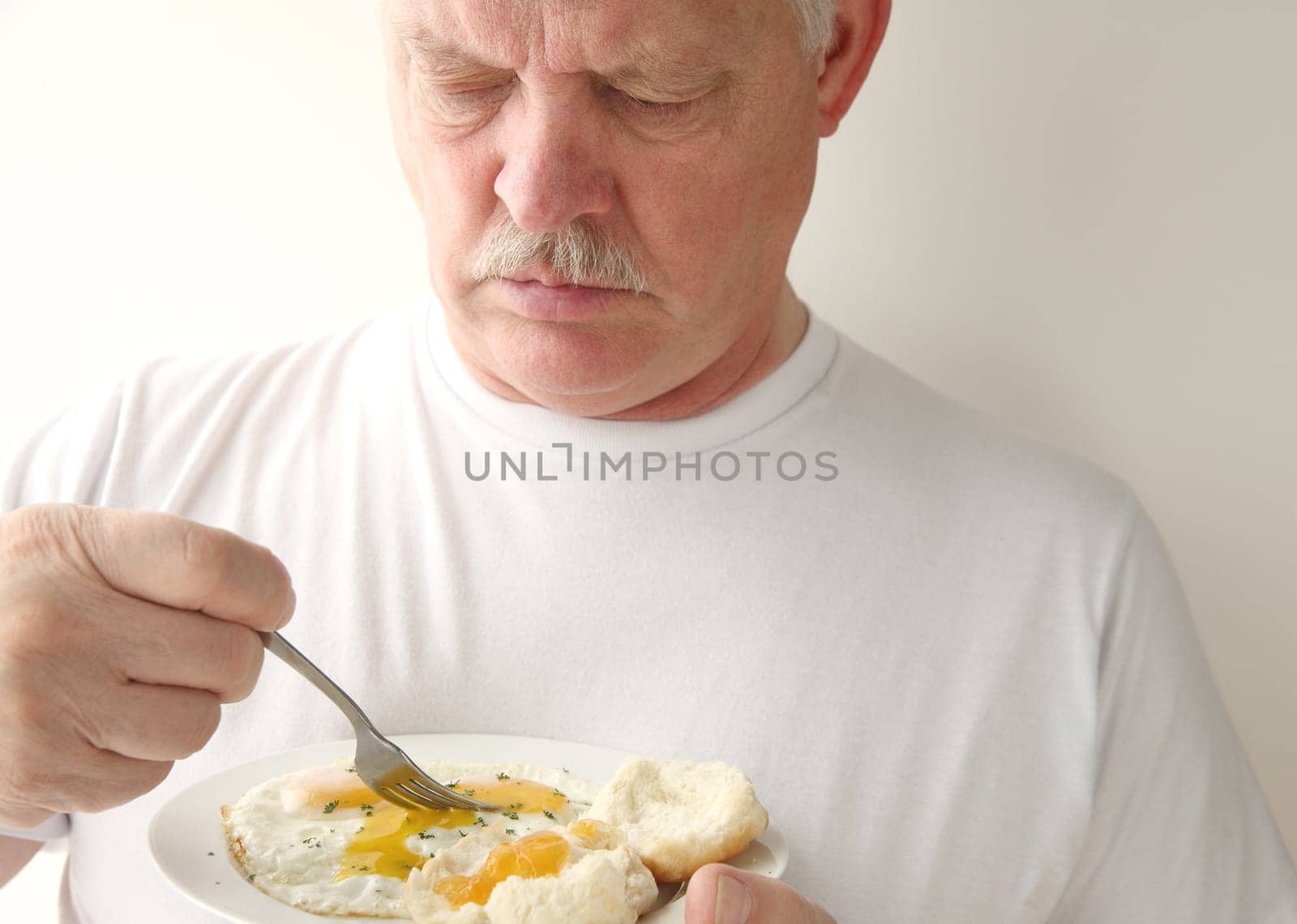 older man eating scrambled eggs with sausage and cornbread