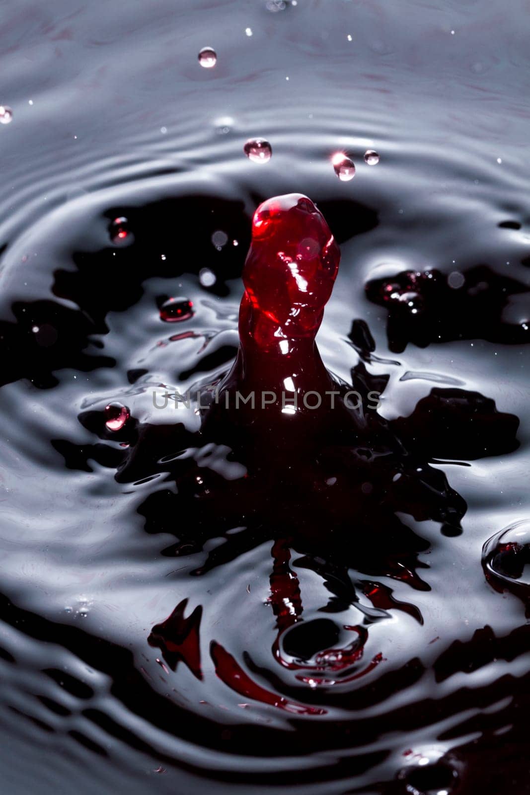 Close view of a droplet of wine hitting a surface of wine.