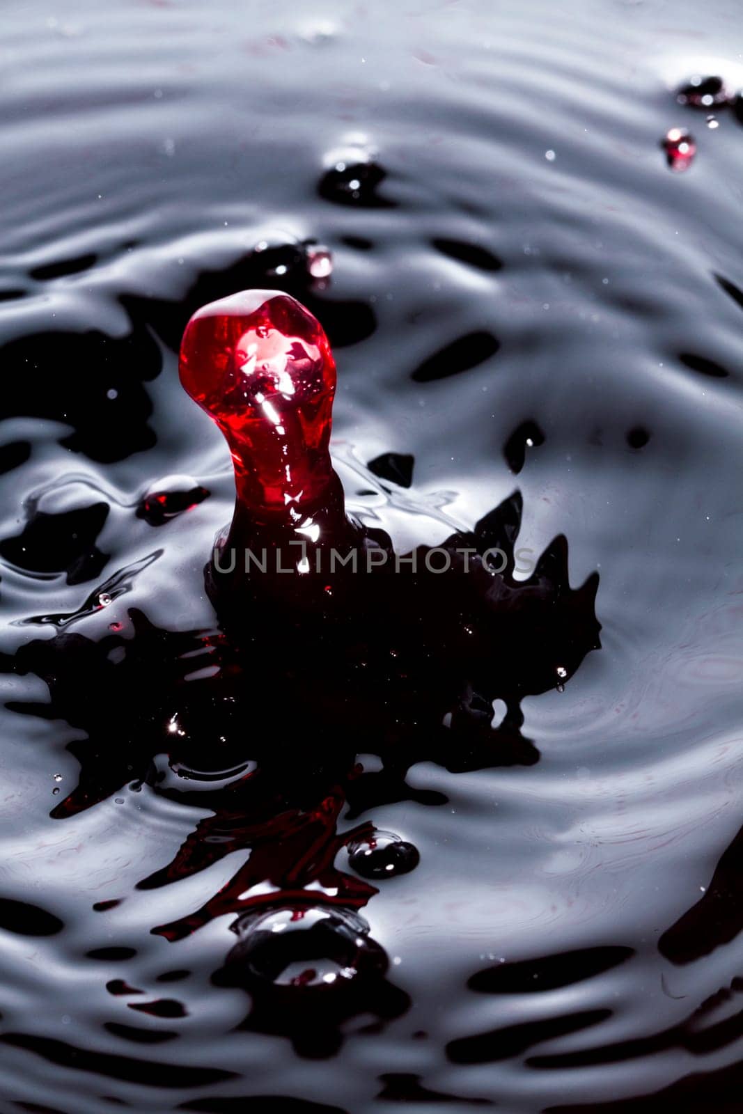 Close view of a droplet of wine hitting a surface of wine.