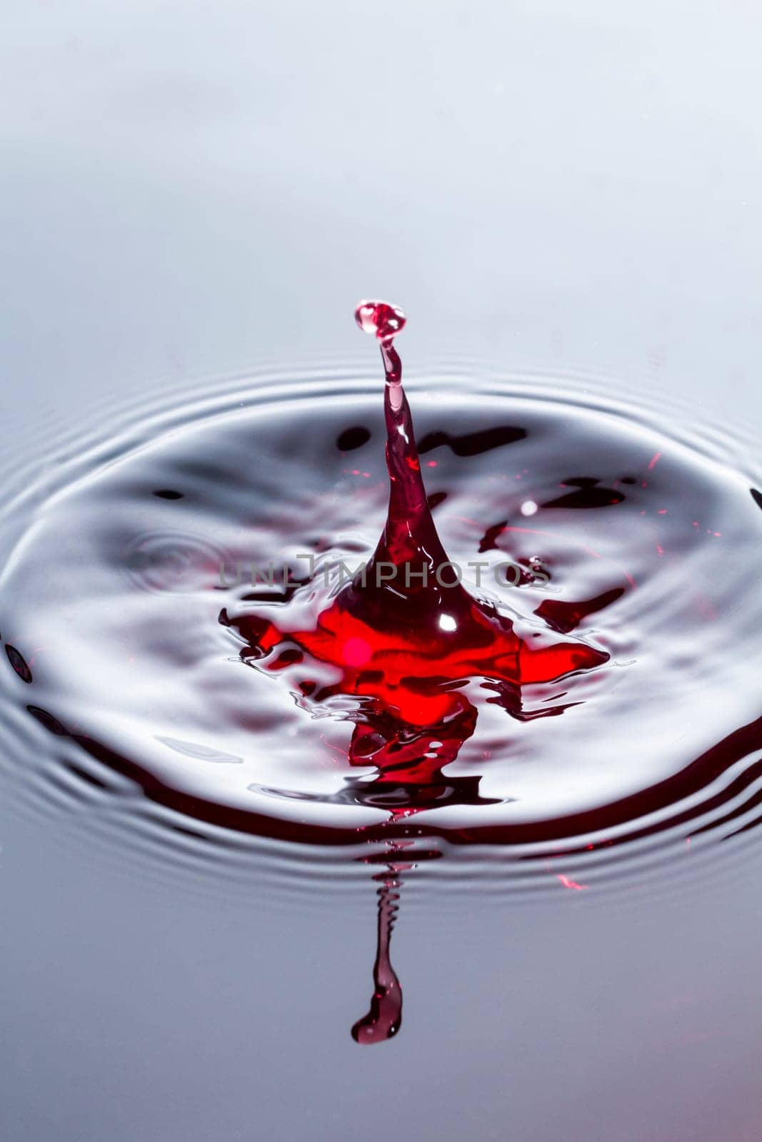 Close view of a droplet of wine hitting a surface of wine.