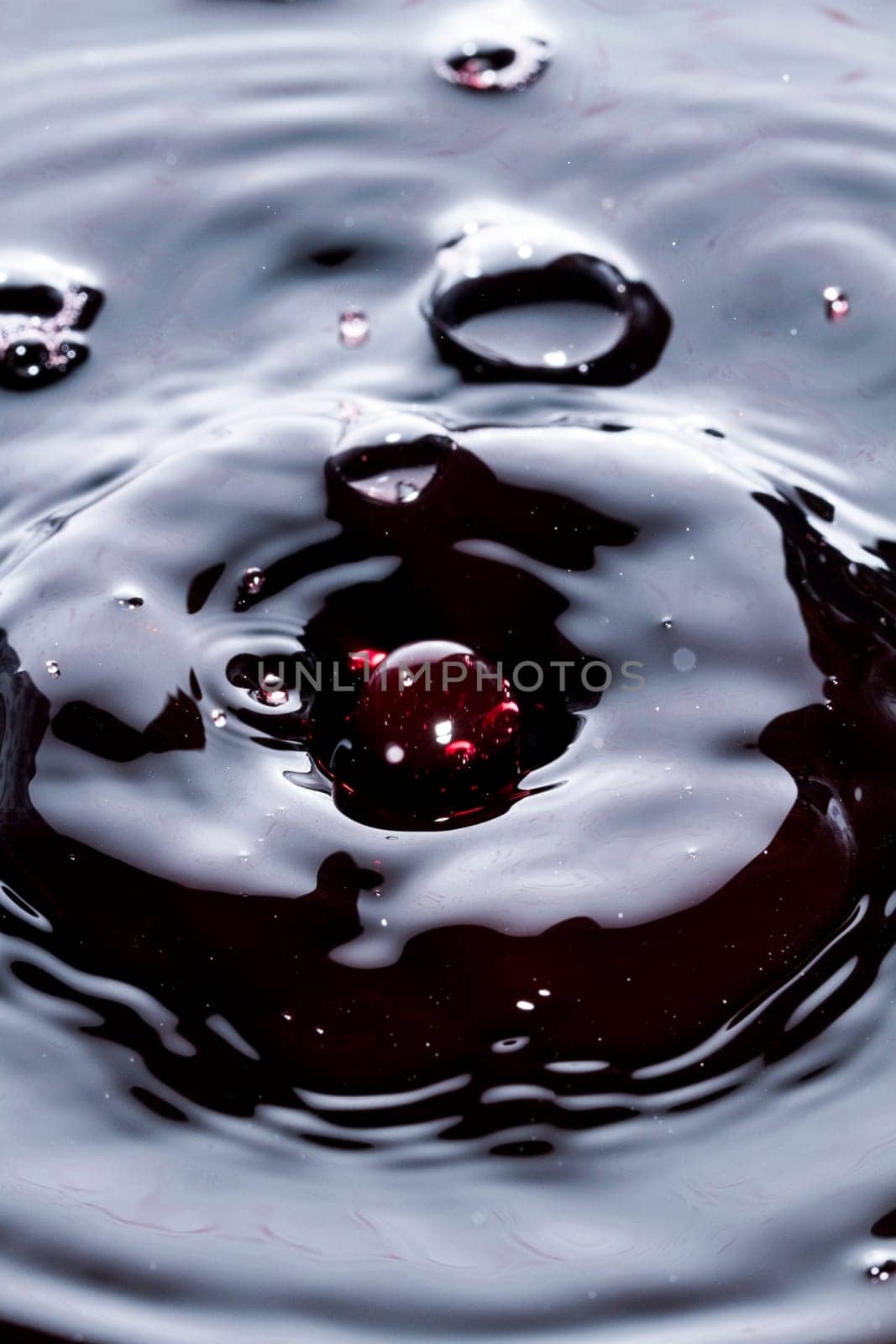 Close view of a droplet of wine hitting a surface of wine.
