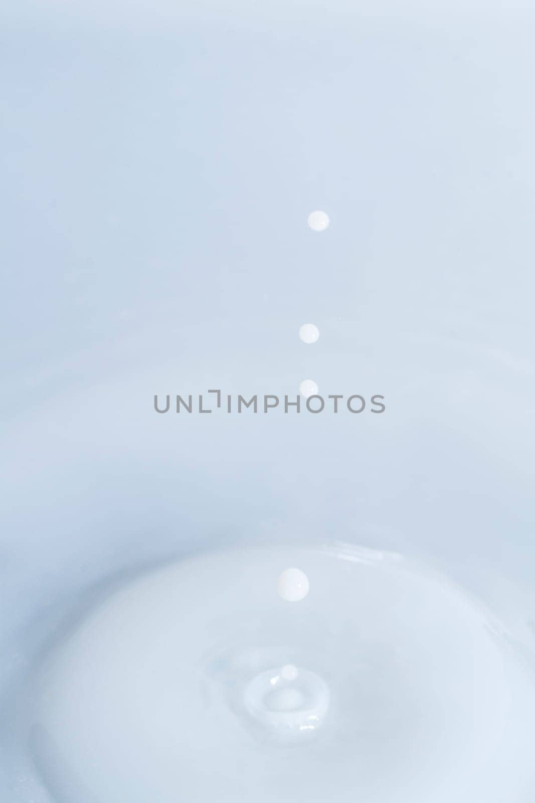 Close view of a droplet of milk hitting a surface of milk.