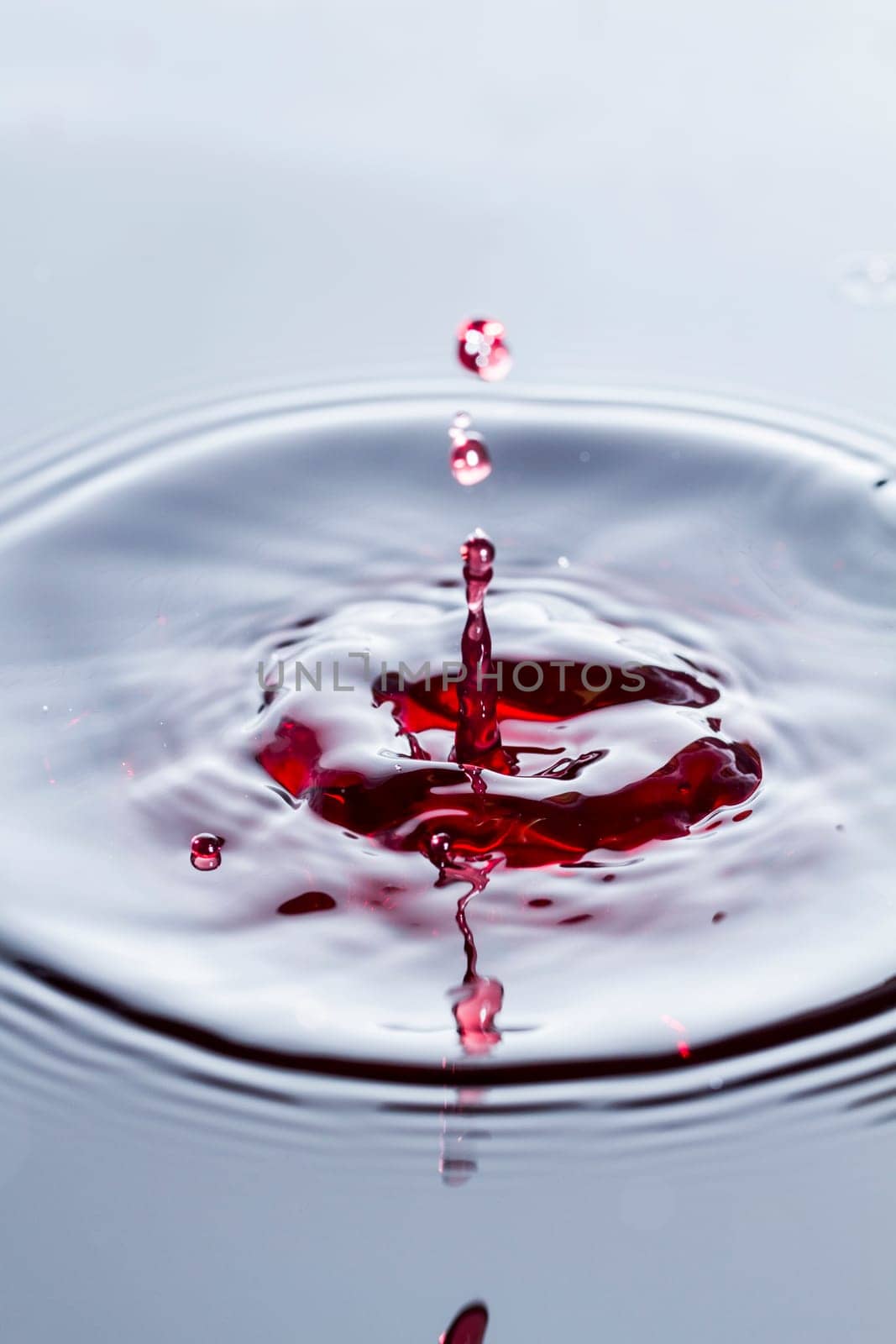 Close view of a droplet of wine hitting a surface of wine.