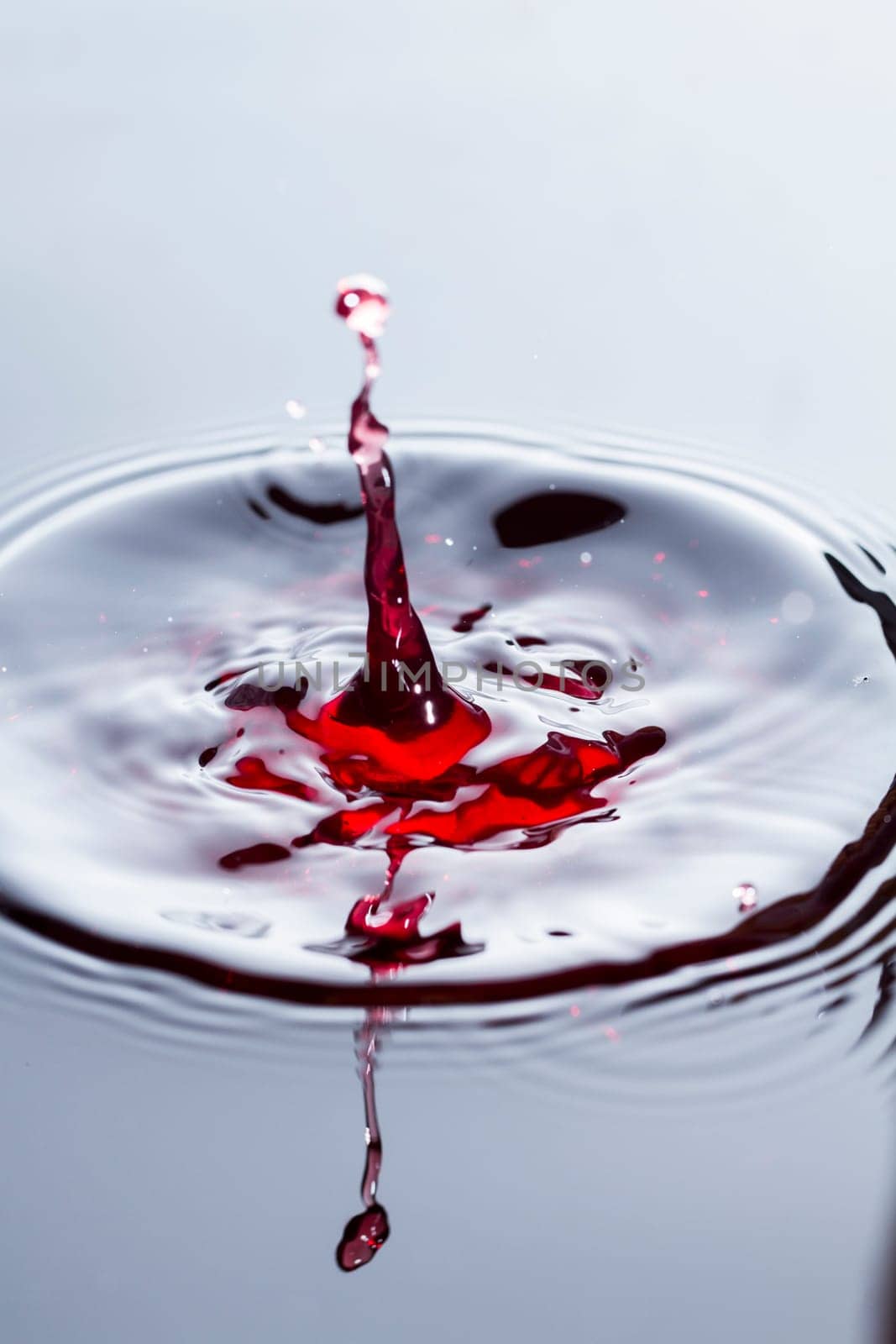 Close view of a droplet of wine hitting a surface of wine.
