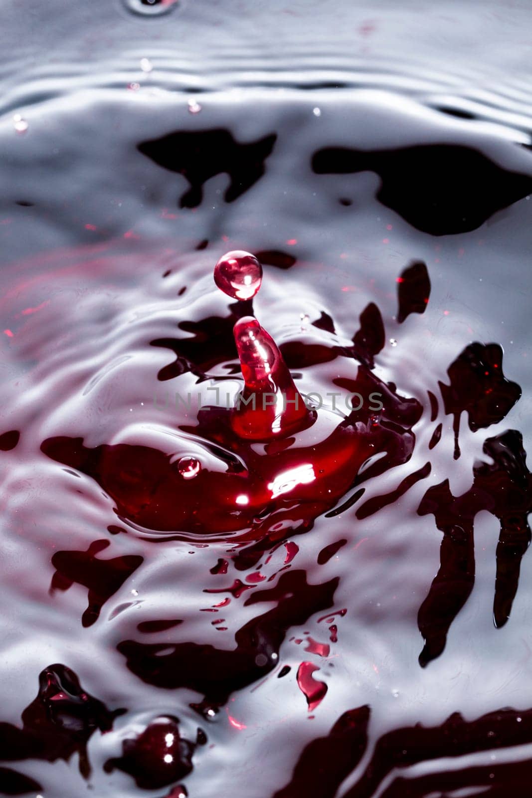 Close view of a droplet of wine hitting a surface of wine.
