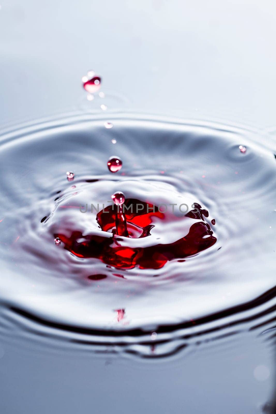 Close view of a droplet of wine hitting a surface of wine.