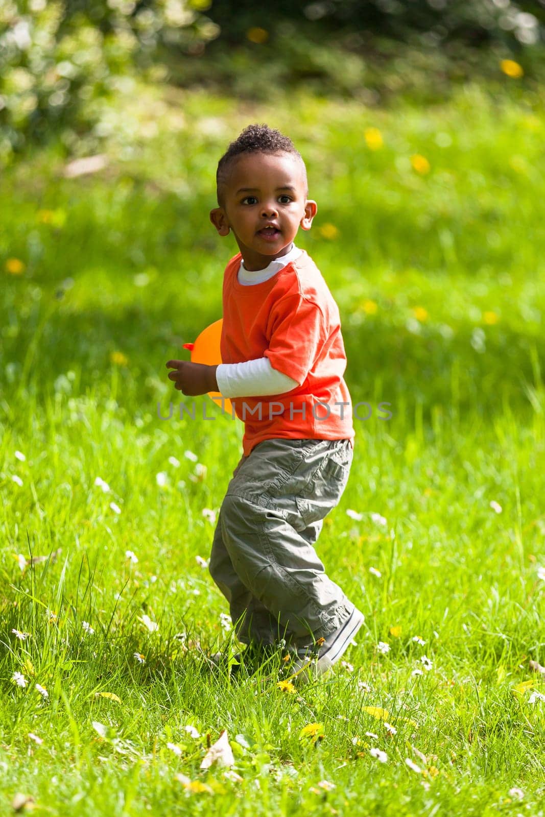 Outdoor portrait of a cute young  little black boy playing with a balloon - African people