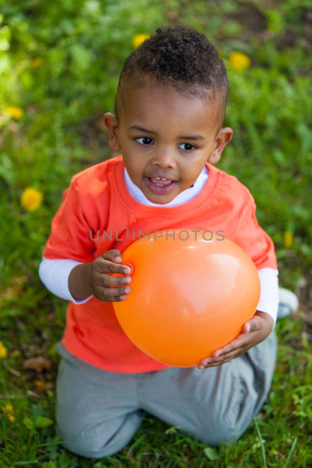 Outdoor portrait of a cute young  little black boy playing with a balloon - African people