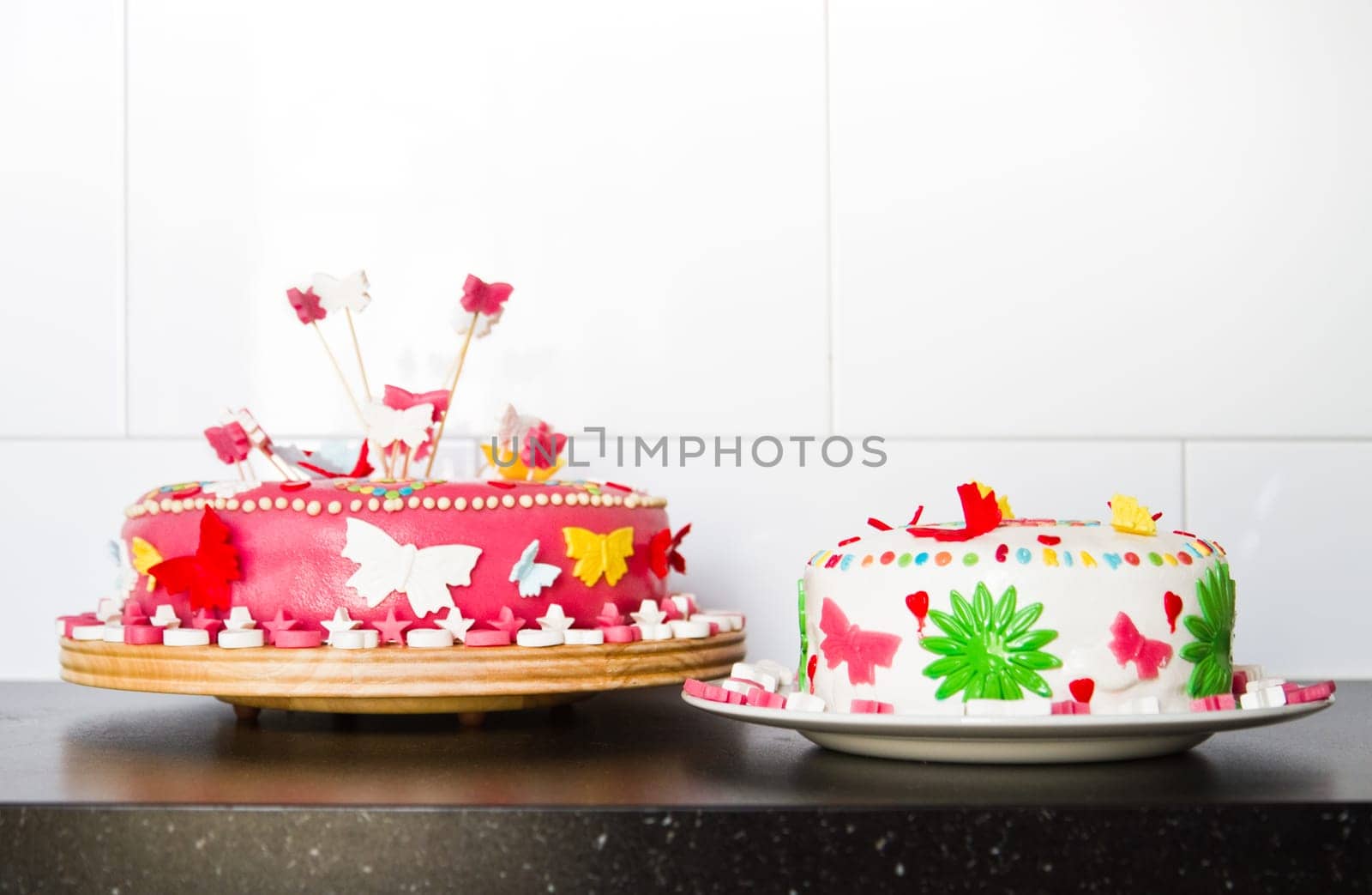 Colorful decorated white and pink Marzipan cakes for a birthday party on kitchen dresser