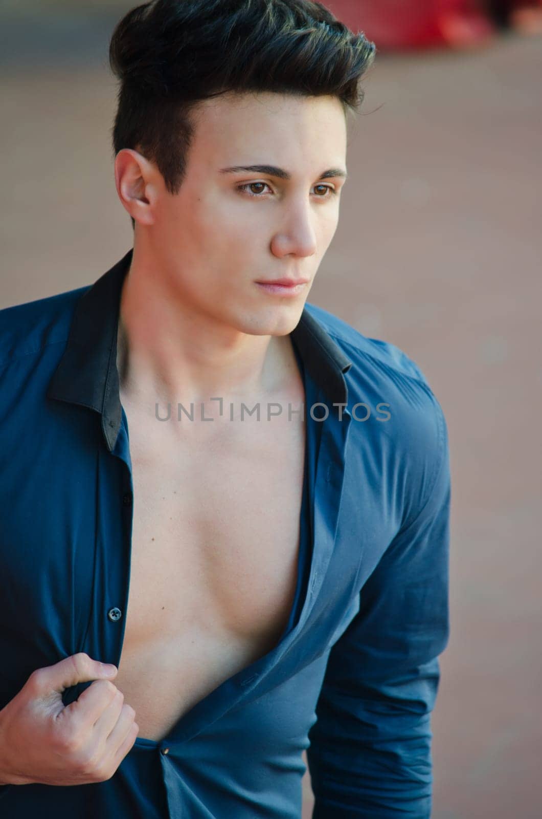 Attractive and trendy young man standing with shirt open showing torso