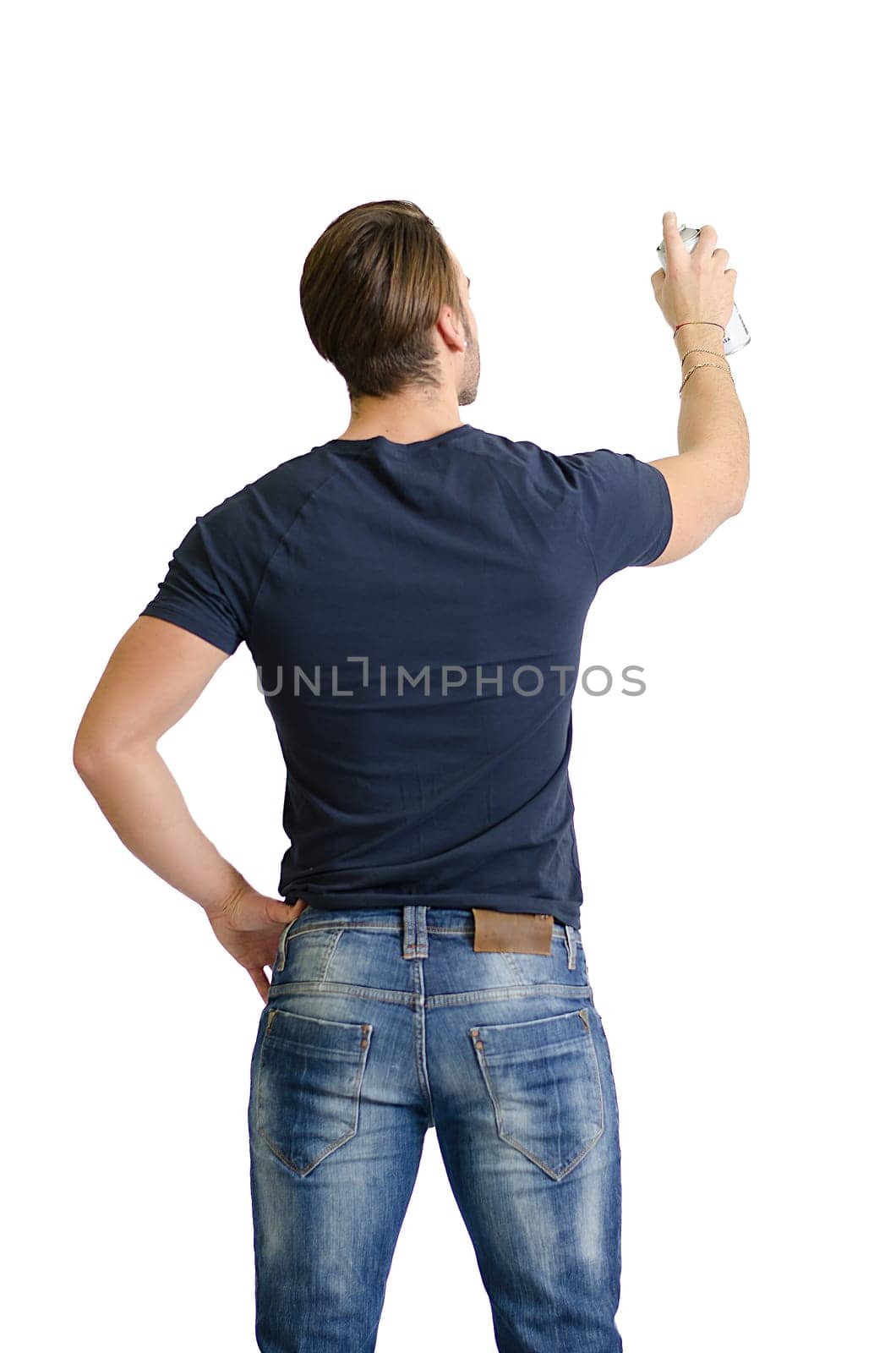 Back of young man with spray paint drawing or writing on empty, blank space seen from behind