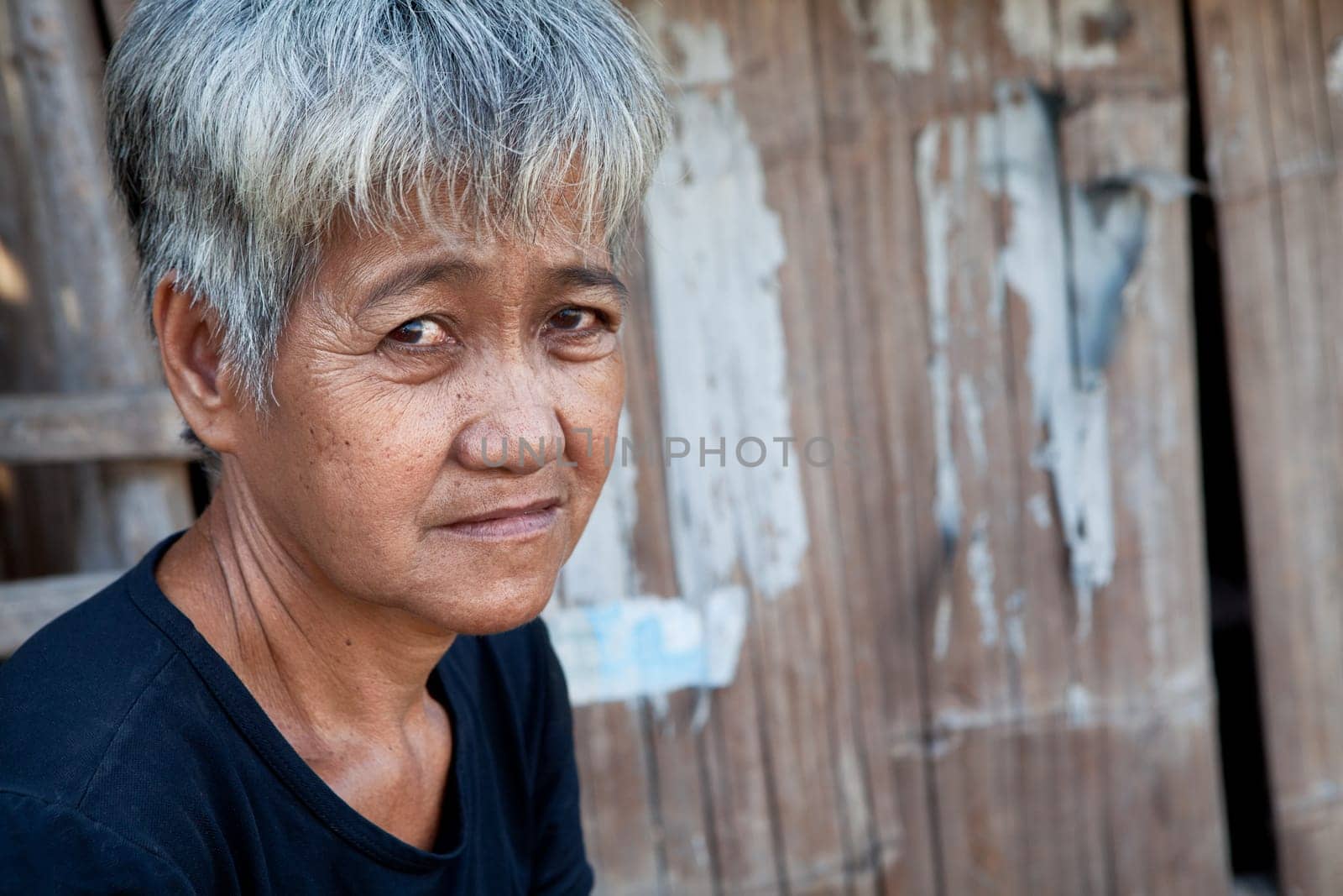Asian senior from an impoverished area, outside her home in the Philippines