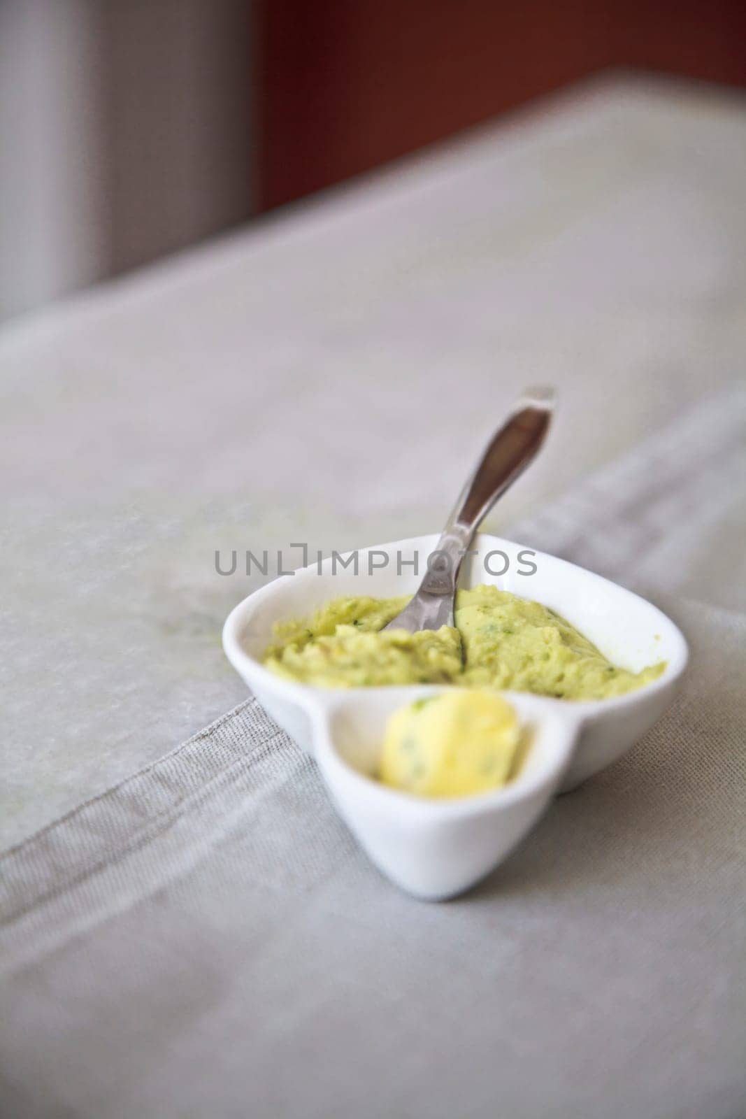 Vertical capture of a porcelain chin butter boat and knife on a whire table cloth furniture with a table runner