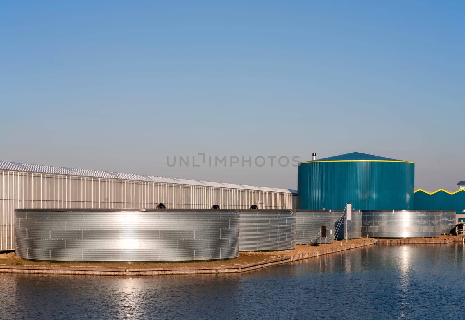 Greenhouse and water tank under a clear blue sky