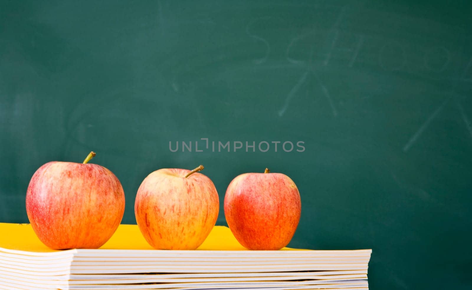 Three apples in a row with used green chalkboard in the background
