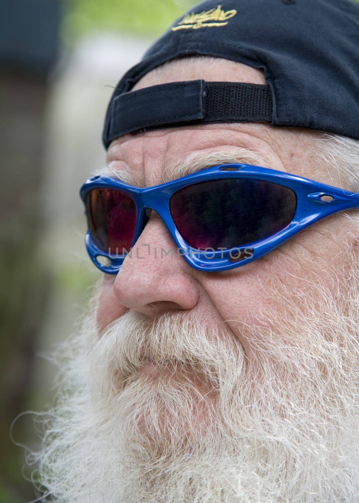Old man with a grey beard with blue sun glasses