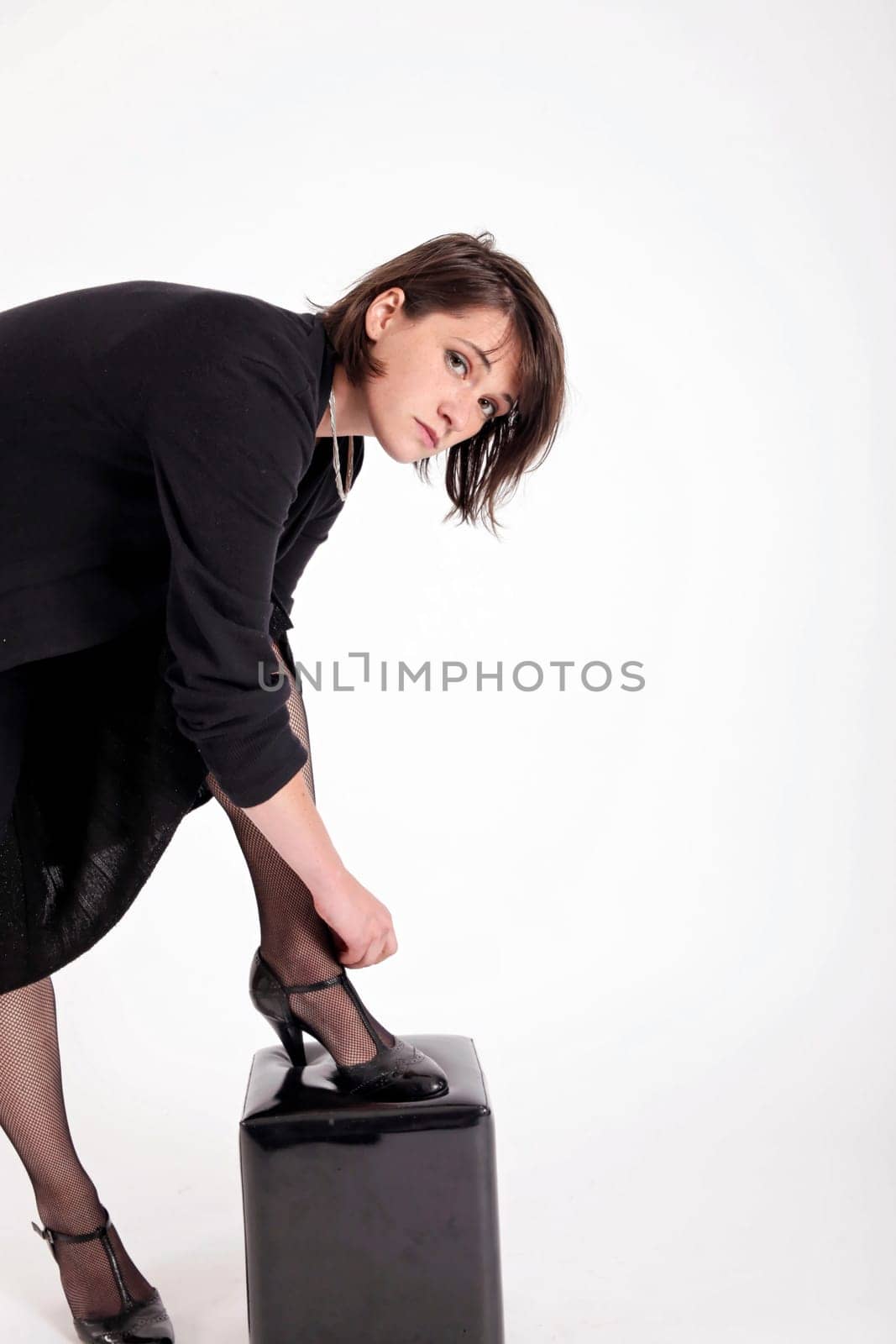 a young woman in strict black dress in studio looking like widow or nanny