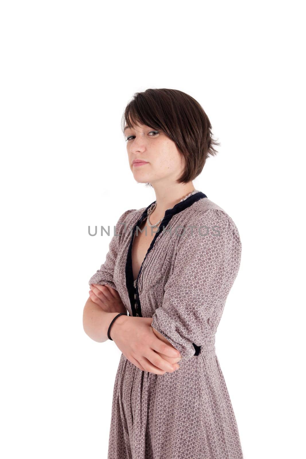 portrait of a young woman in grey dress arms crossed on studio