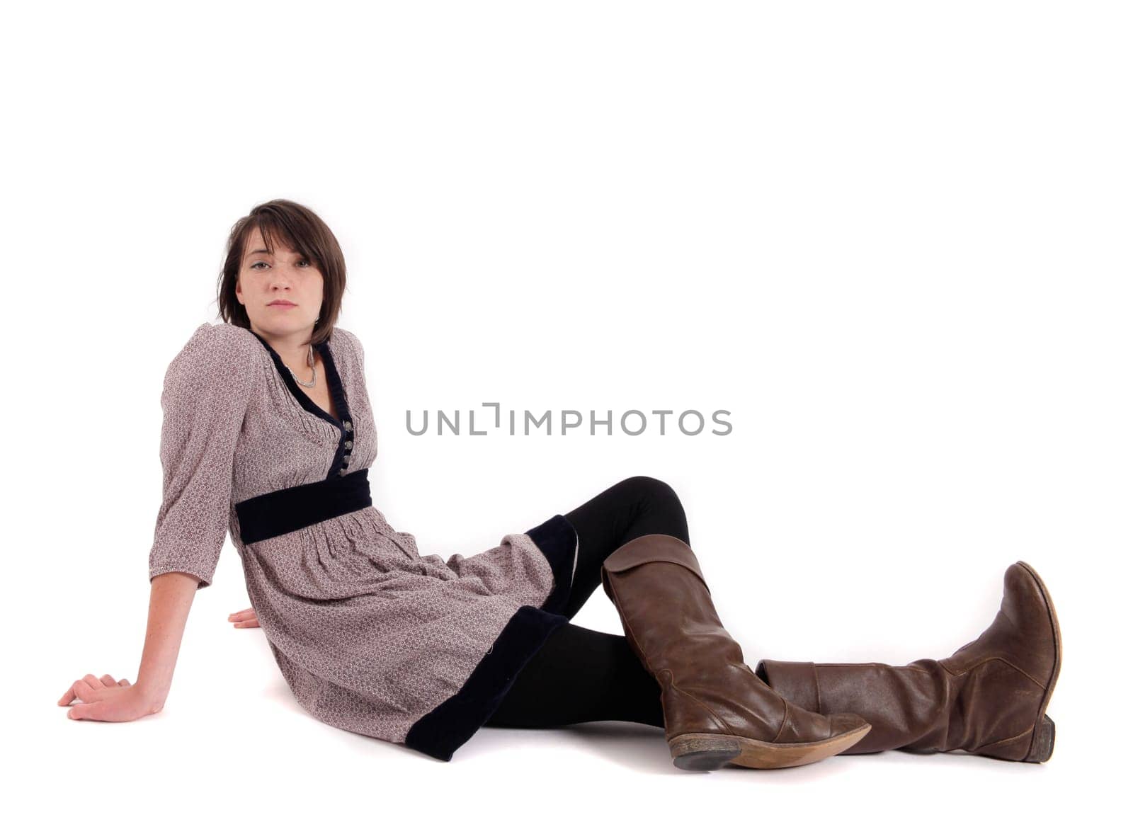 young brunette woman in dress sitting on the ground with boots