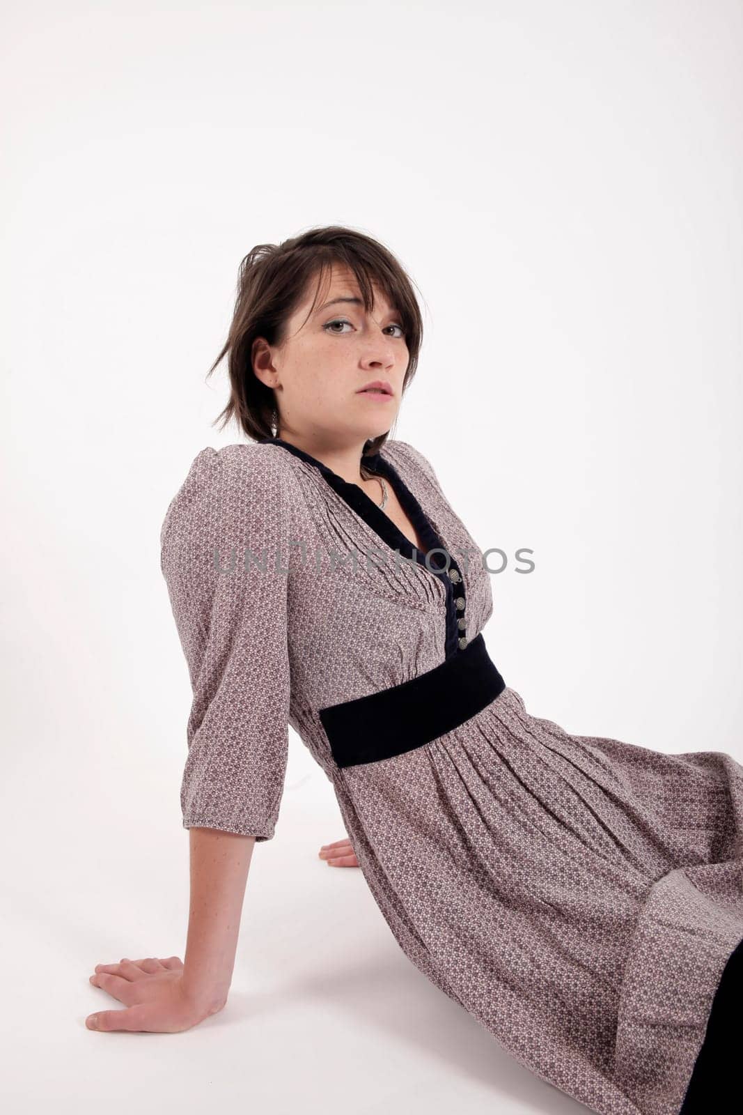 young brunette woman in dress sitting on the ground with boots