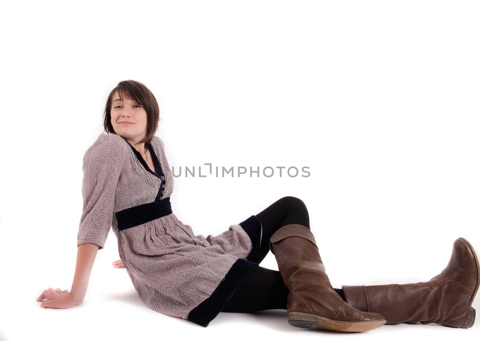 young brunette woman in dress sitting on the ground with boots