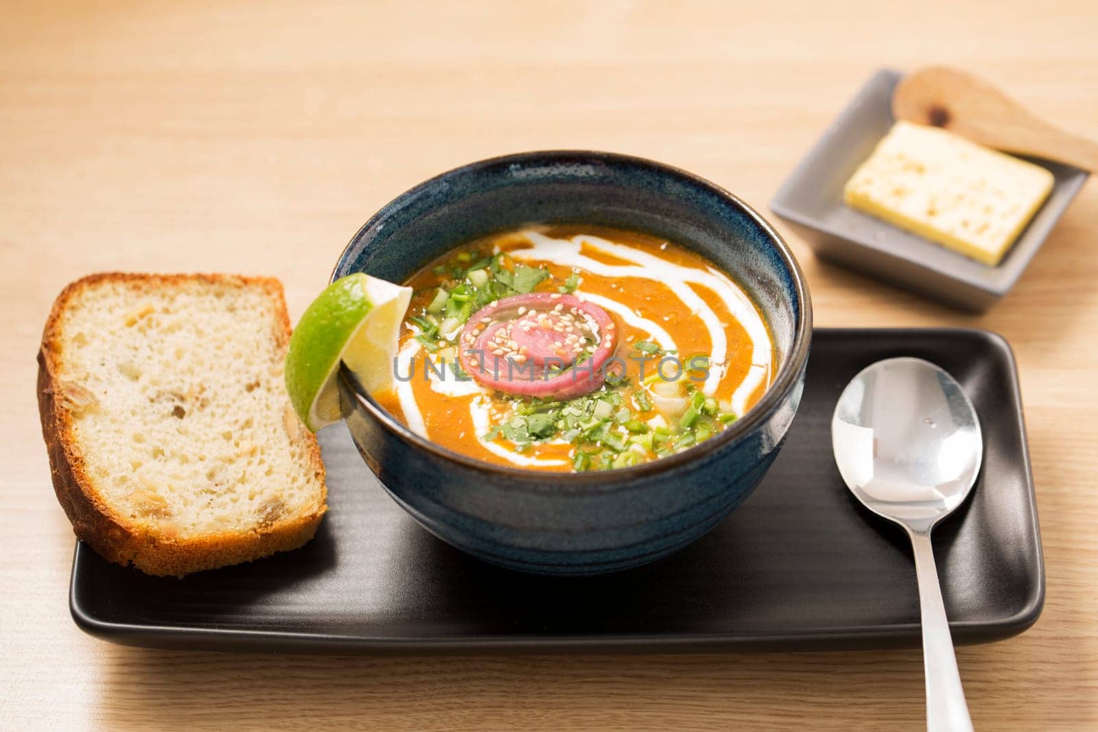 Bowl with reflective soup with spoon and bread