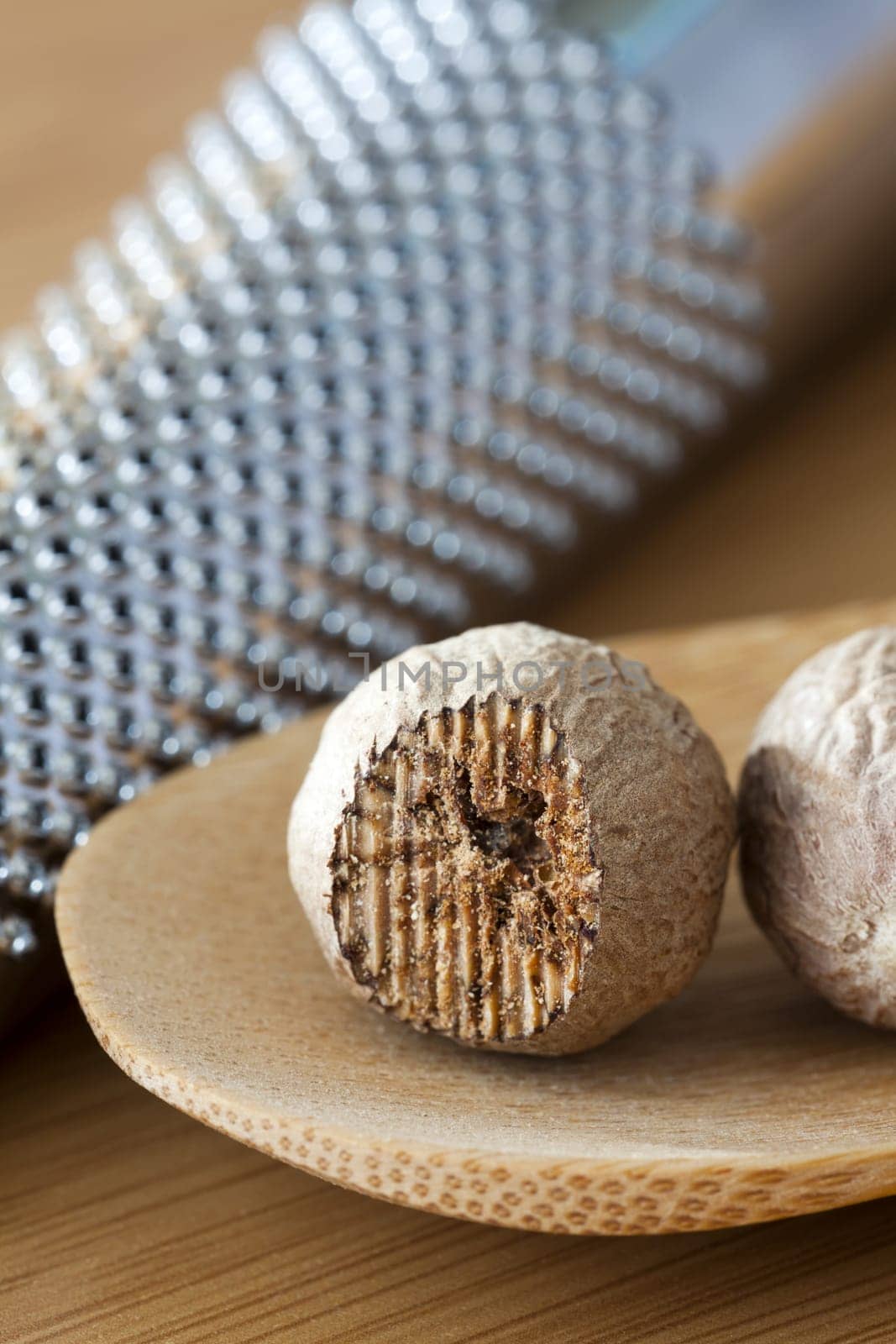 Two nutmegs on a wooden spoon and in the background a musca drive out of focus