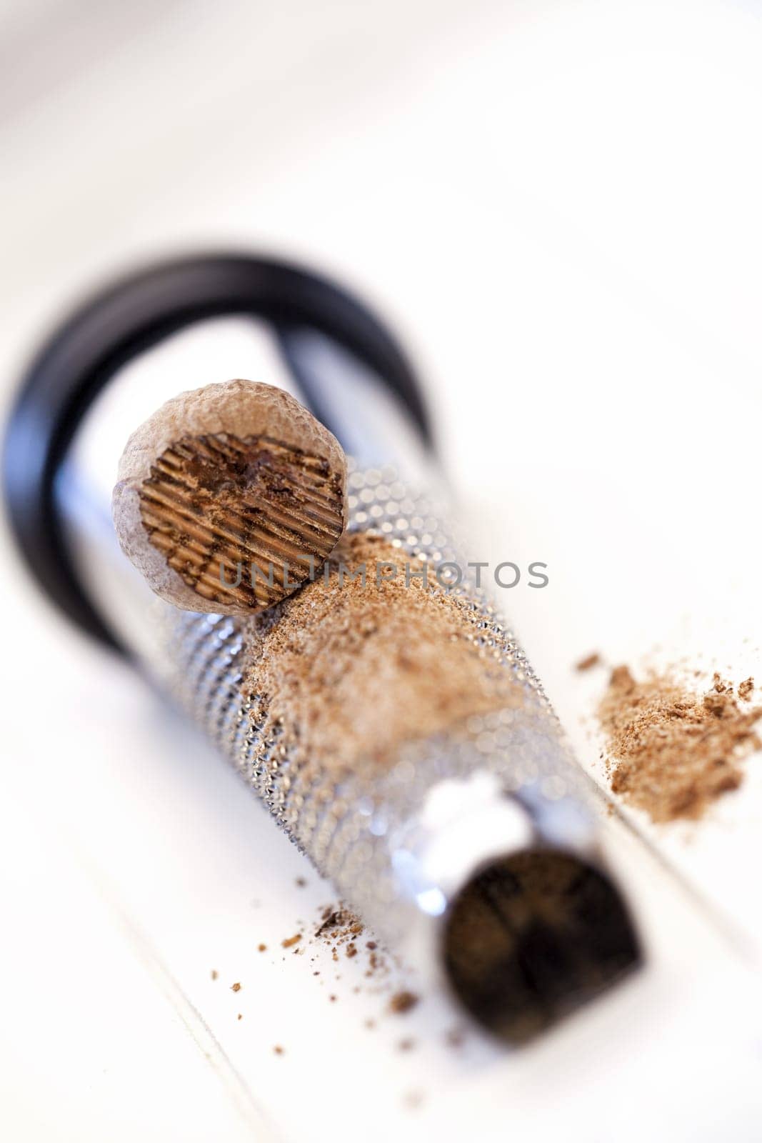 Nutmeg lies on a nutmeg grater on a white background
