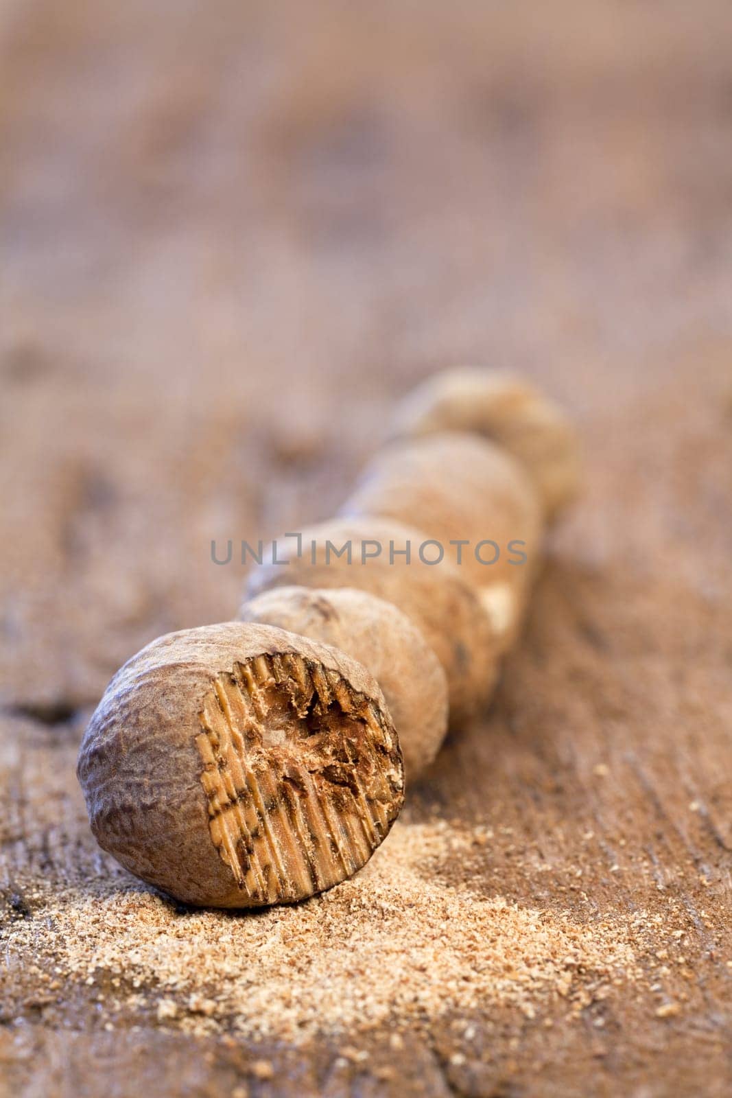 Five nutmegs in a row on a rustic wooden surface
