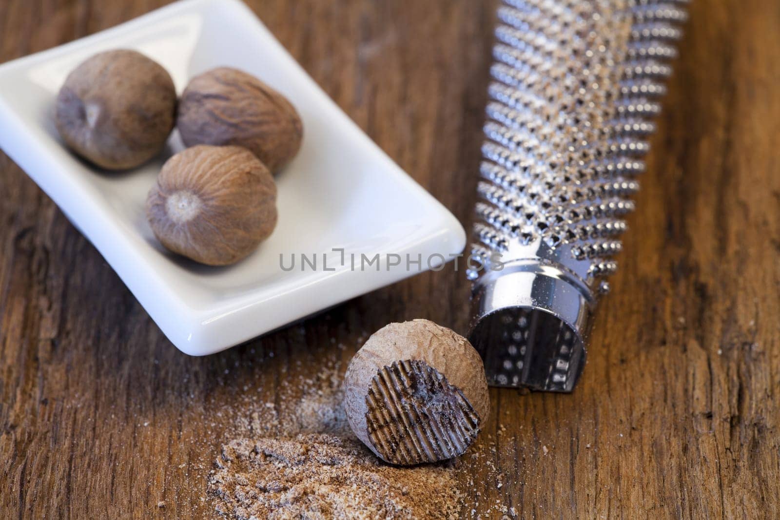 Nutmeg in a bowl and a nutmeg in front of a nutmeg