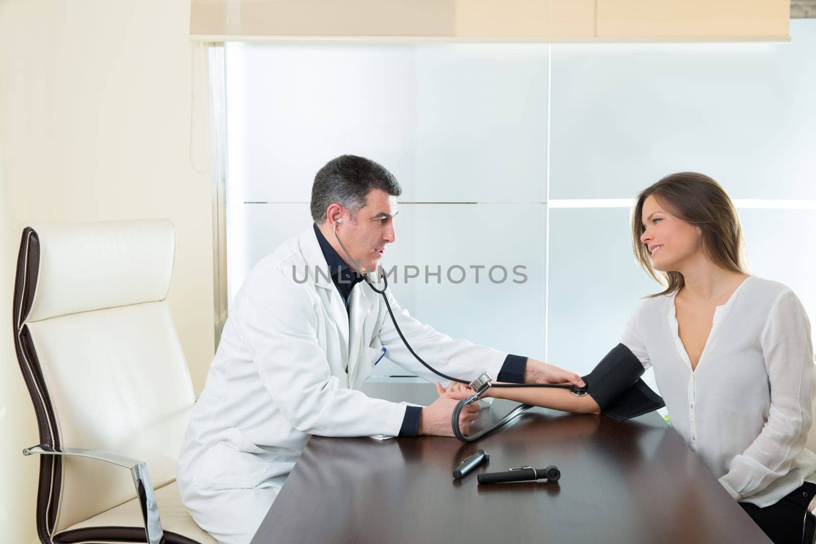 Doctor man checking blood pressure cuff on woman patient arm on hospital office