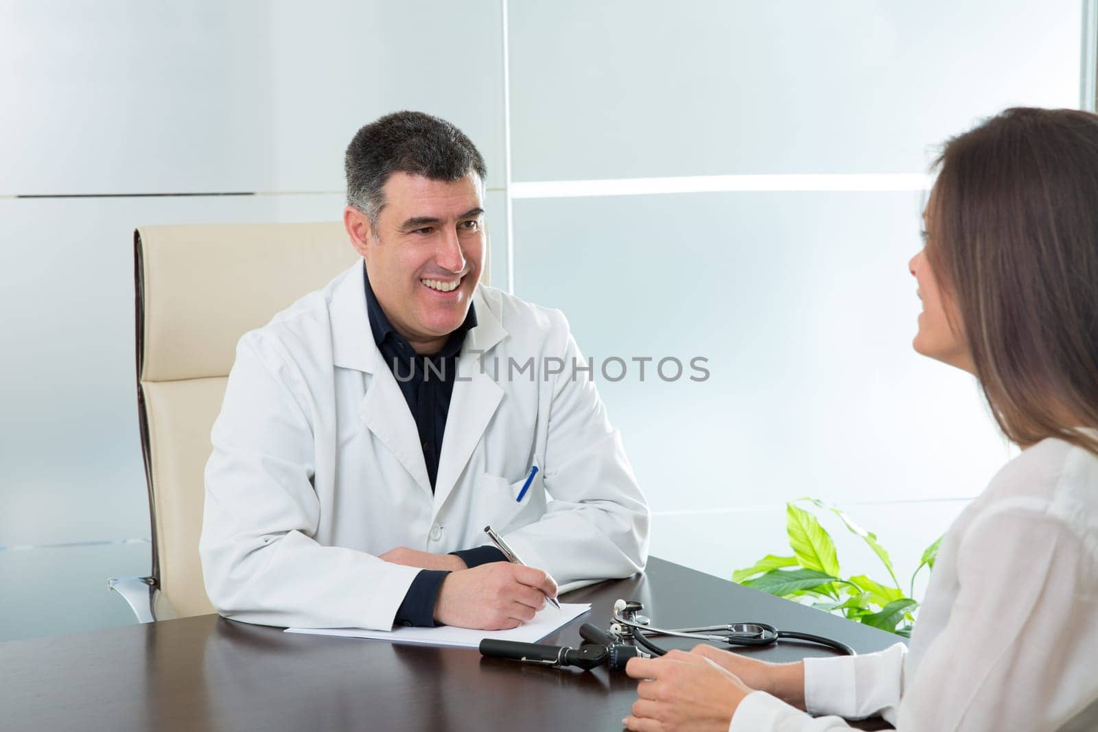 Doctor man and patient woman on hospital office talking on desk
