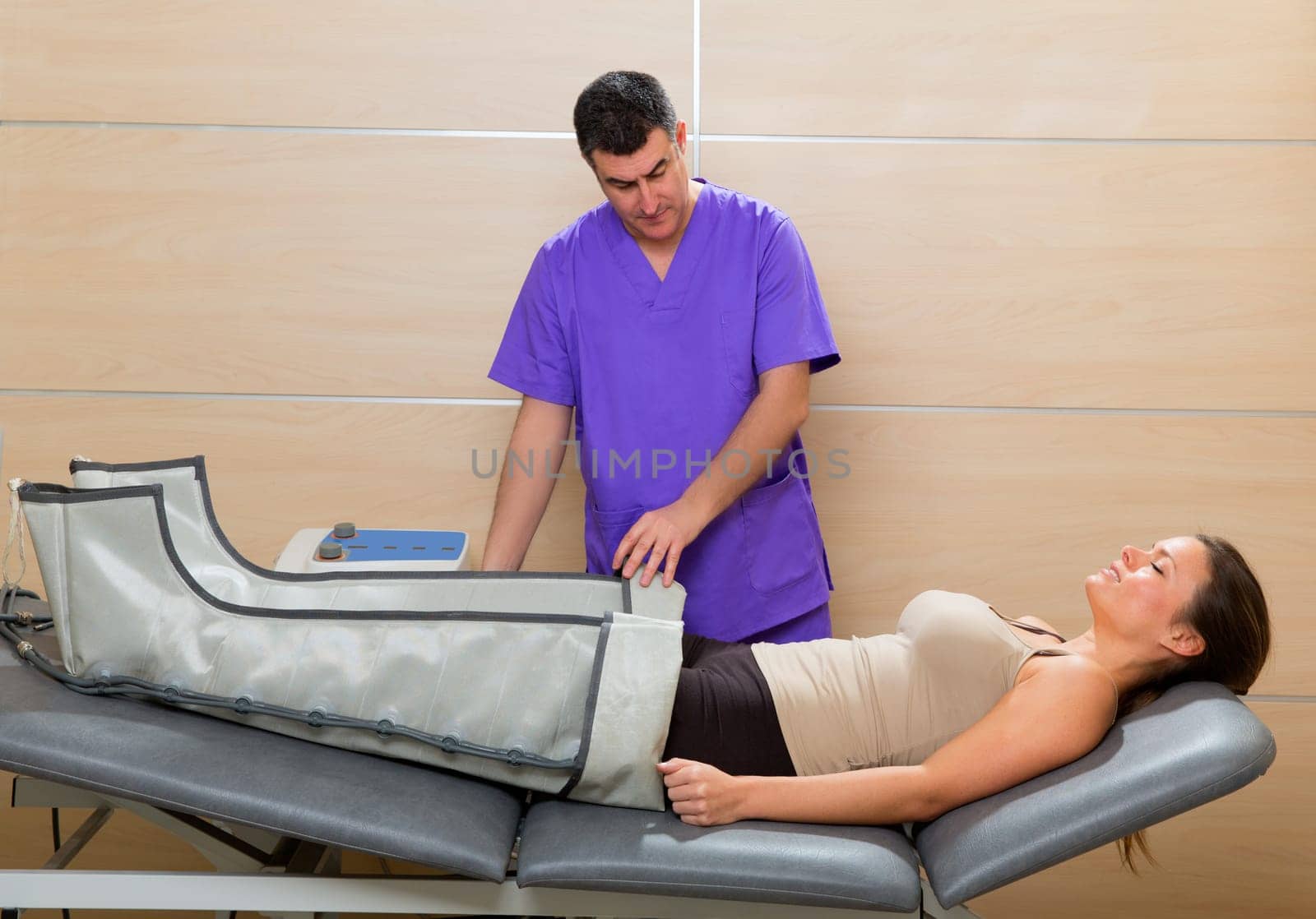Doctor checking legs pressotherapy machine on woman patient in hospital bed