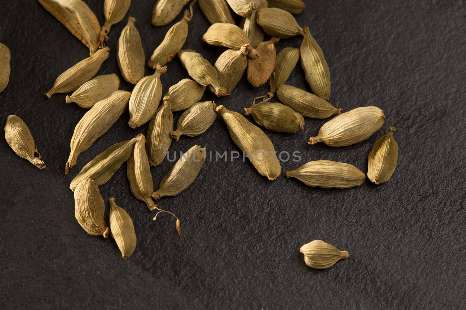 cardamom spice macro detail over black slate stone background