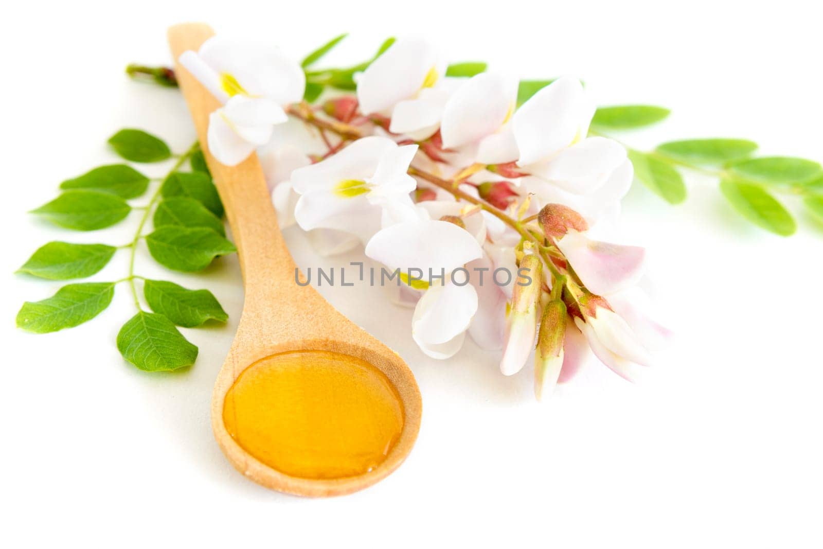 Honey in spoon with acacia flower on white background