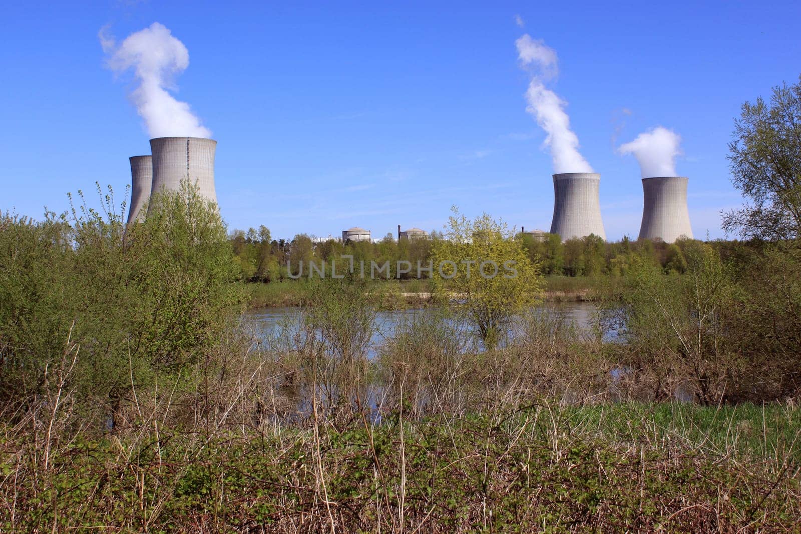 photo of an operating nuclear power plant on the banks of a river surrounded by trees