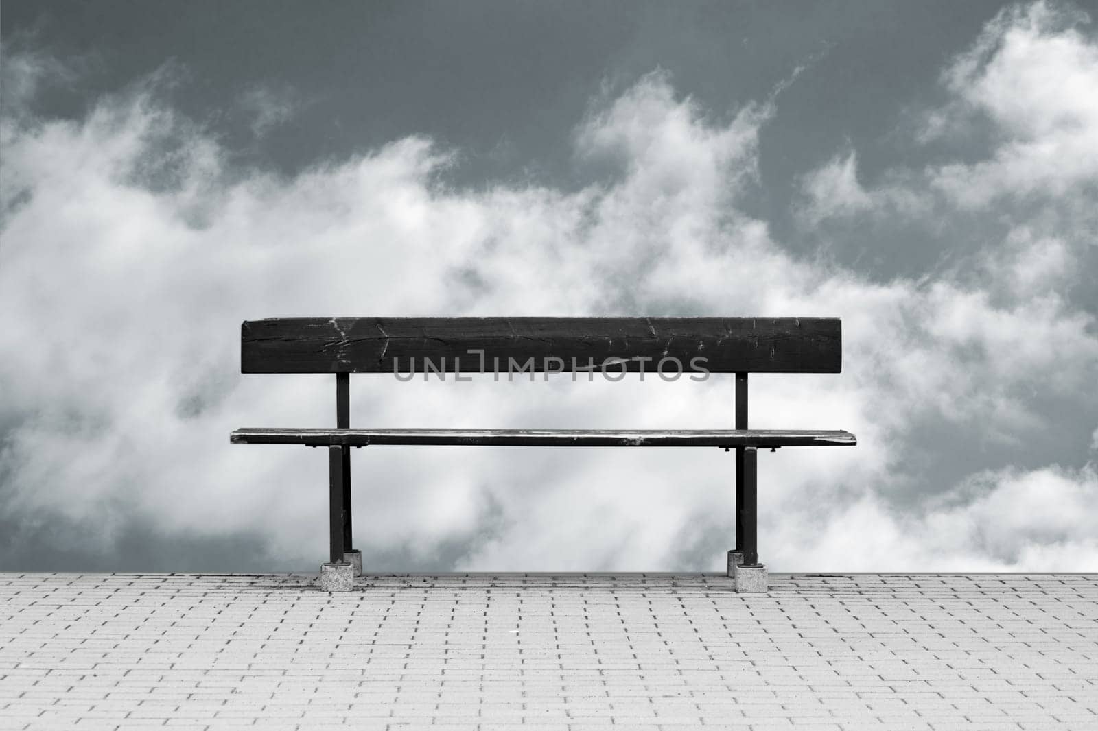 The photograph of a free-standing park bench against a sky background.