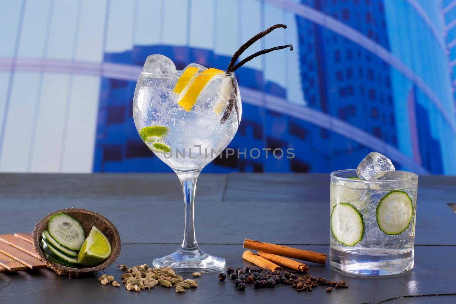 Gin tonic cocktail with spices in urban city buildings background