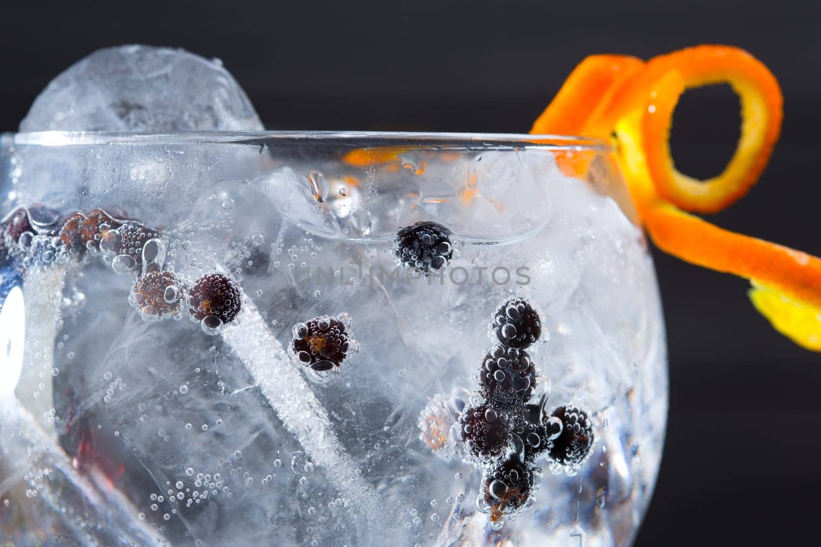 Gin tonic cocktail macro closeup with juniper berries orange