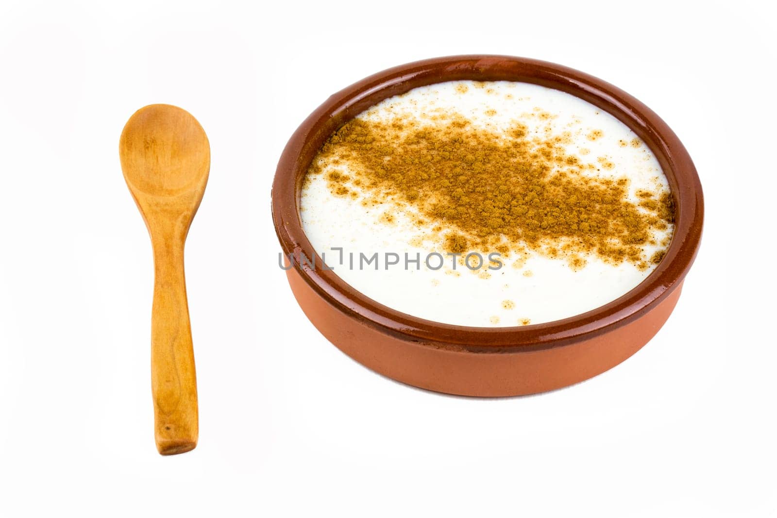 homemade rice with milk and cinnamon in a ceramic bowl, presentation with spoon. isolated on white background