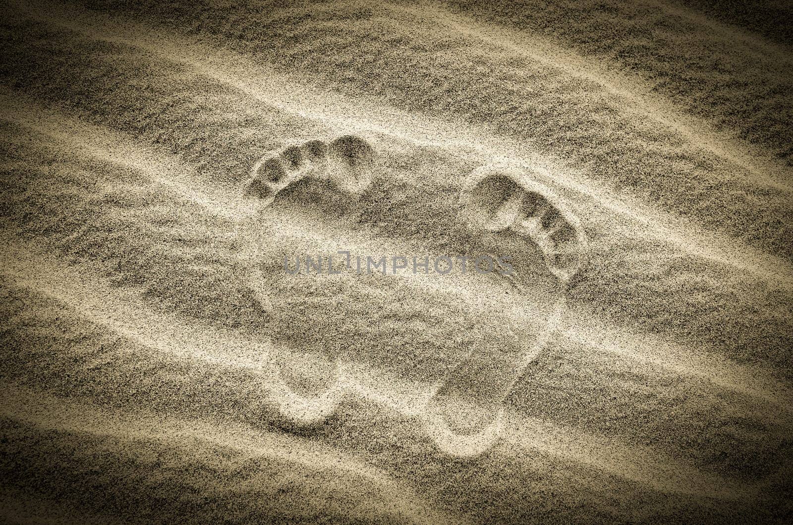 Two footprints in sand on the desert beach, vintage image
